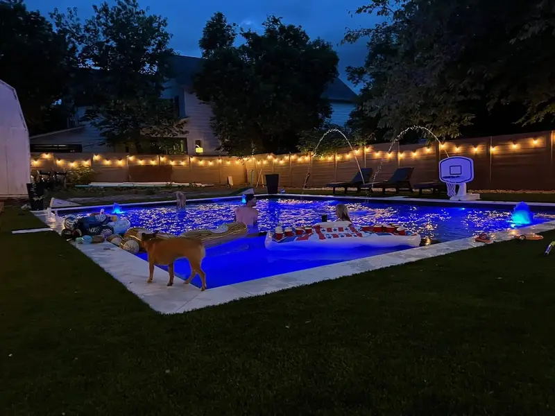Landscape and string lighting around an Austin pool after sunset