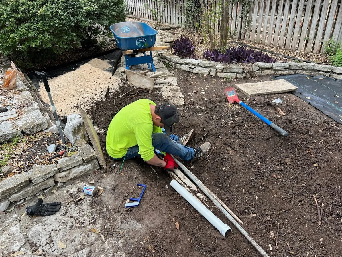 Crew member laying a drain line before the base goes in