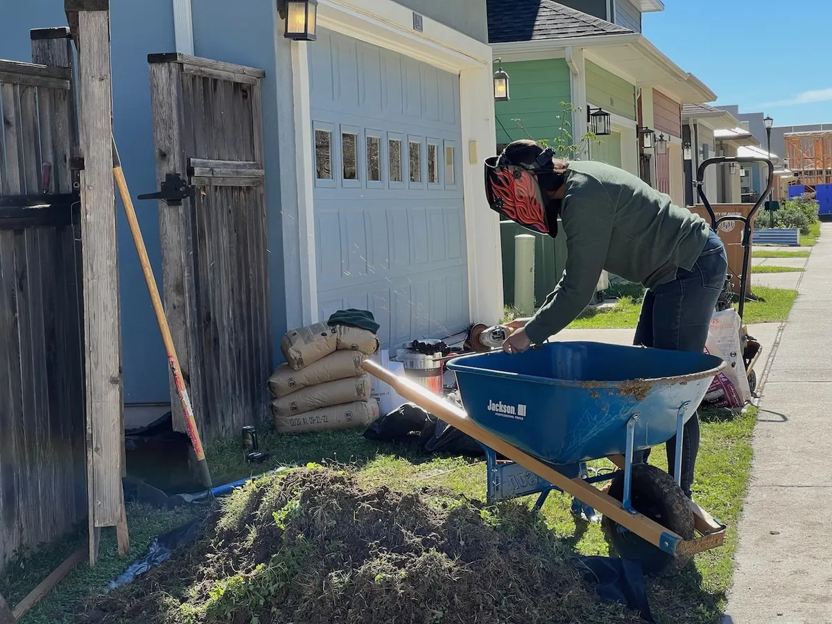 Crew member tearing out old sod with a wheelbarrow